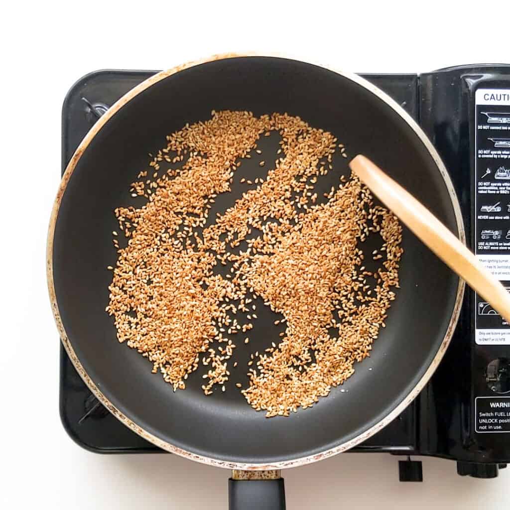 Toasting white sesame seeds in a frying pan.