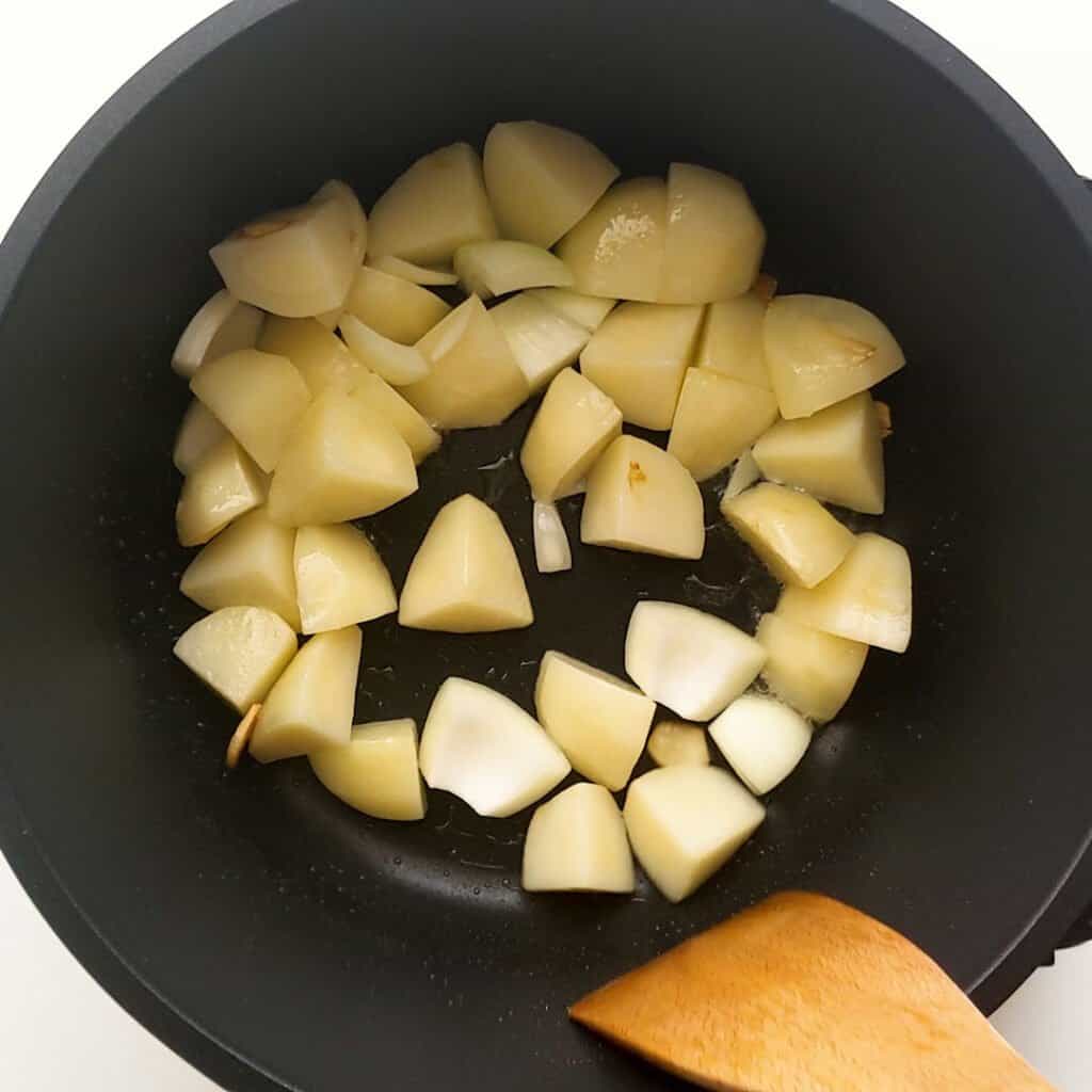 Frying the potato and garlic in the pan.