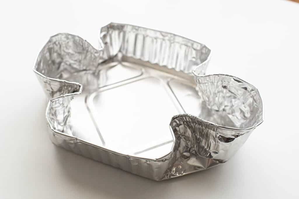 Aluminium tin foil showing corners wrapped into a colomba mould.