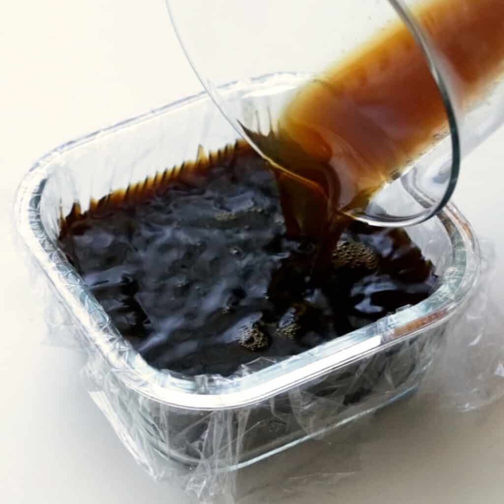 Pouring the coffee jelly into a lined glass dish.