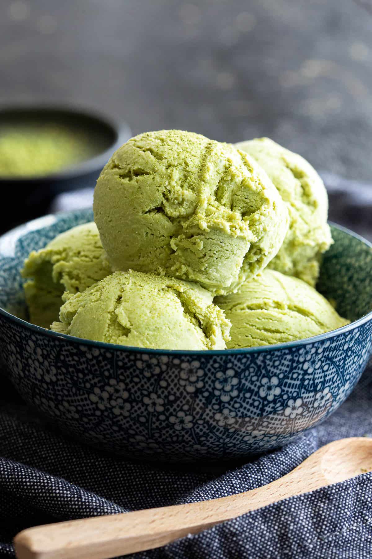 Matcha ice cream in a bowl with a wooden spoon.