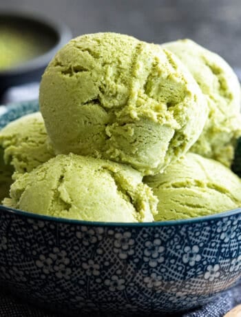 Green tea ice cream scoops in a blue bowl.