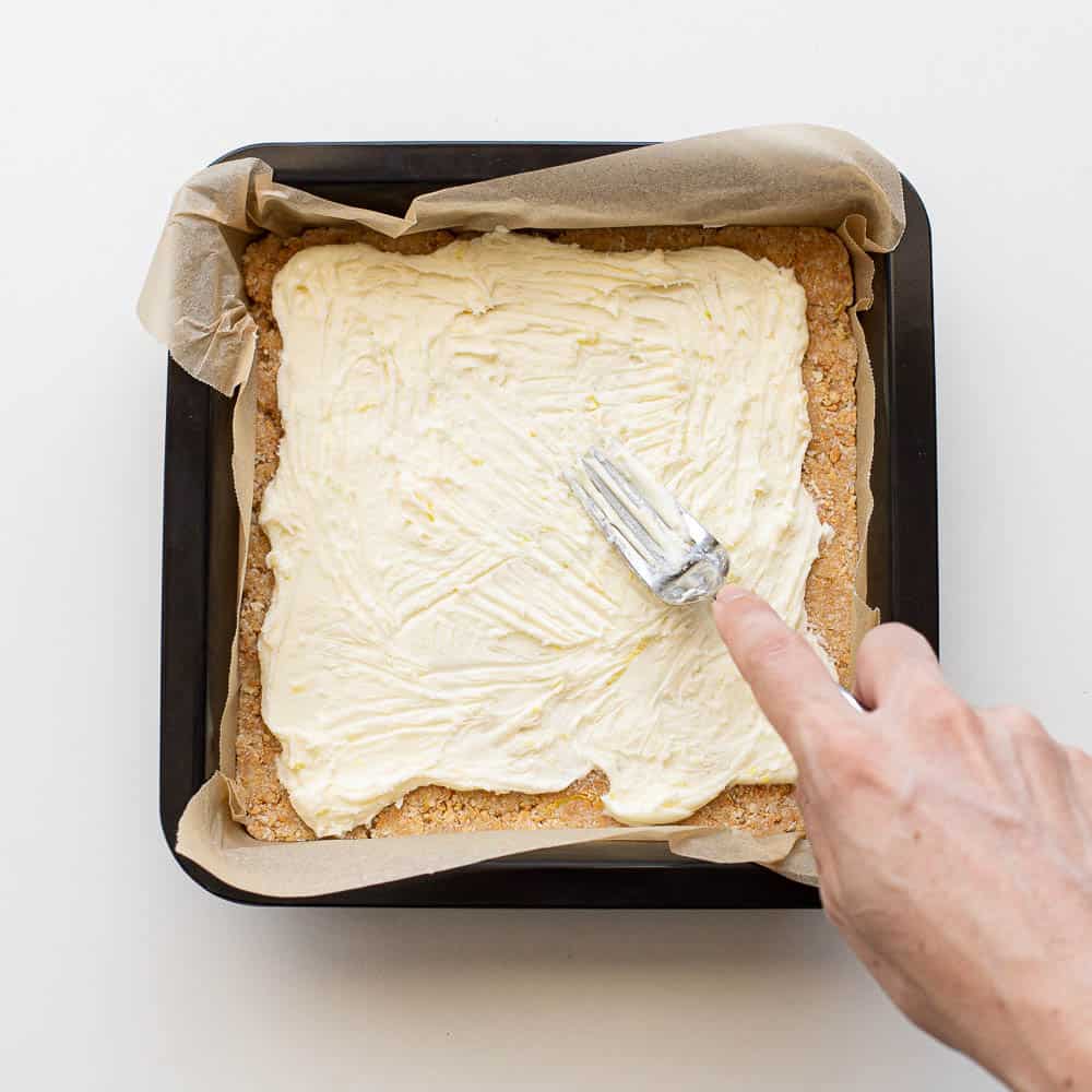 Spreading the lemon icing over the base with a fork.
