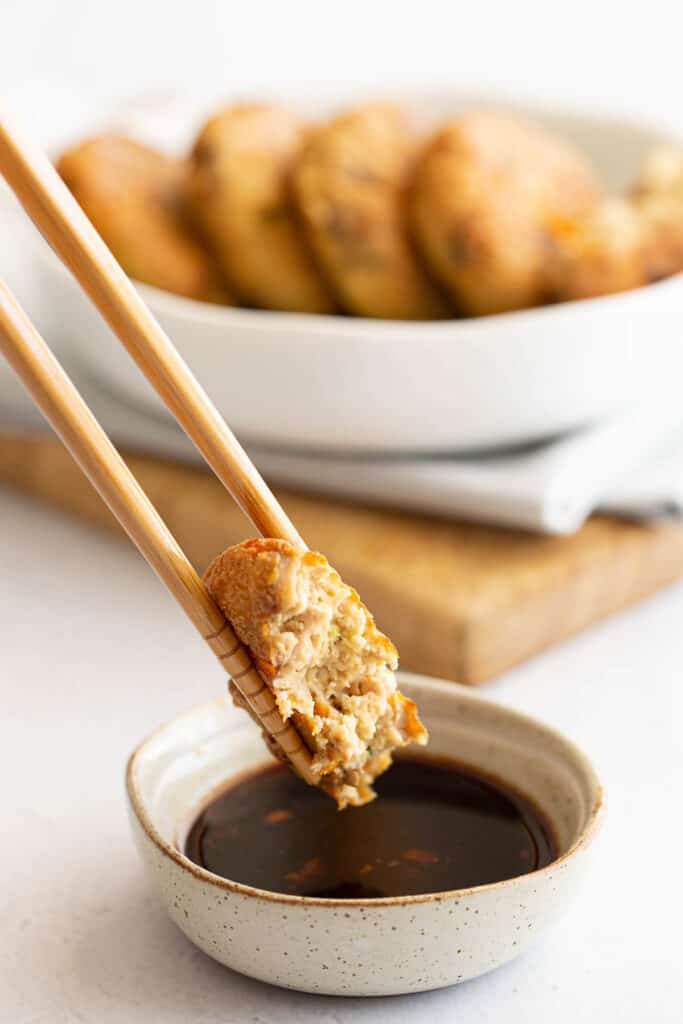 Dipping half a tofu patty into a small soy and ginger dipping sauce.