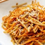 Strips of stir fried carrot and burdock root in a Japanese style sauce.