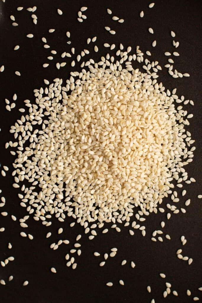White sesame seeds poured out onto a frying pan, ready to toast.