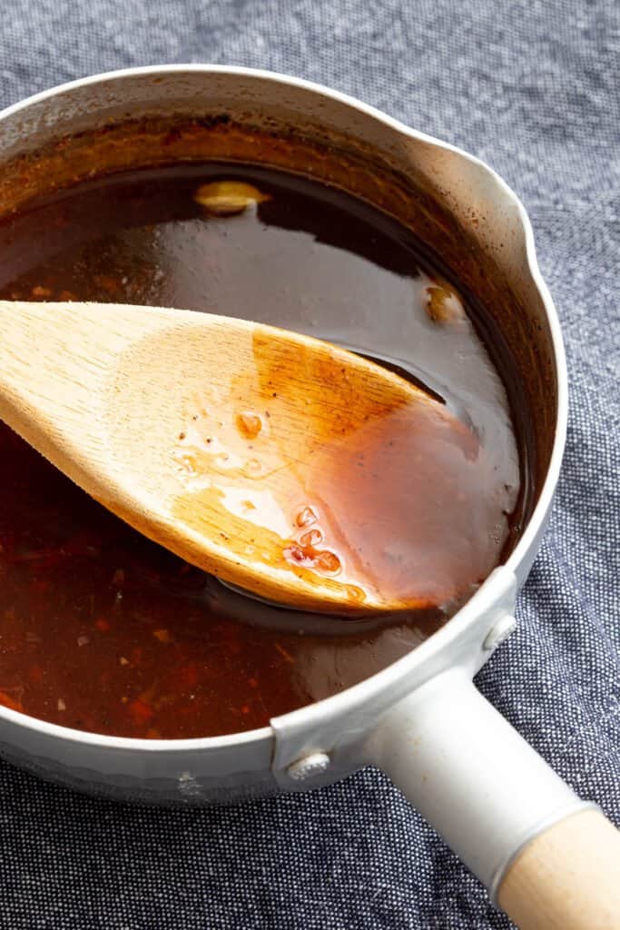 Scooping out some homemade Worcestershire sauce in a saucepan.