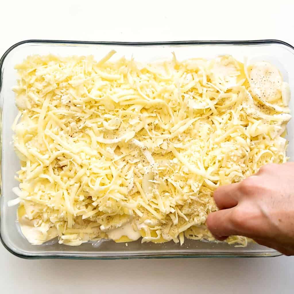 Topping potato bake with tasty shredded cheese.