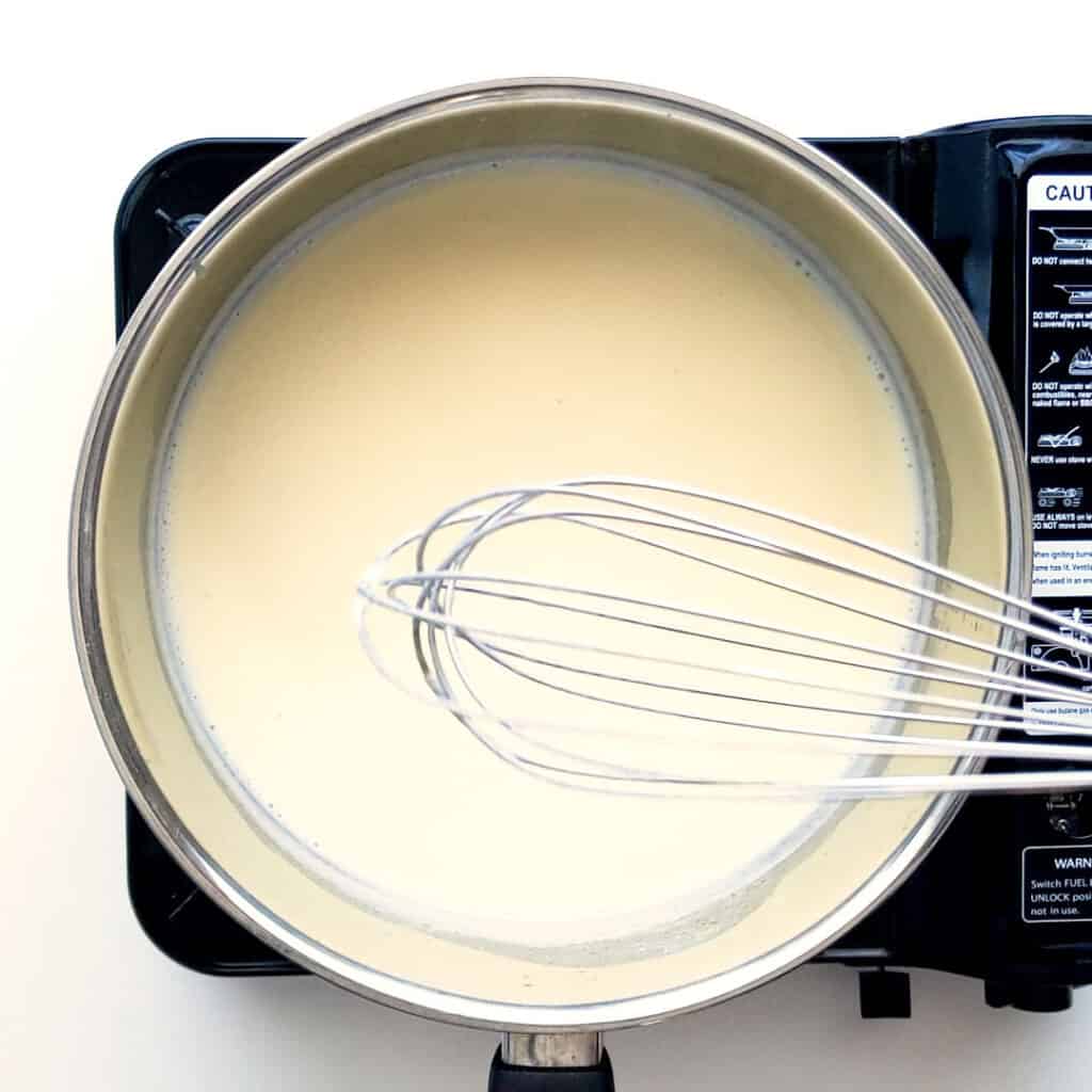 Whisking white sauce together until thick.