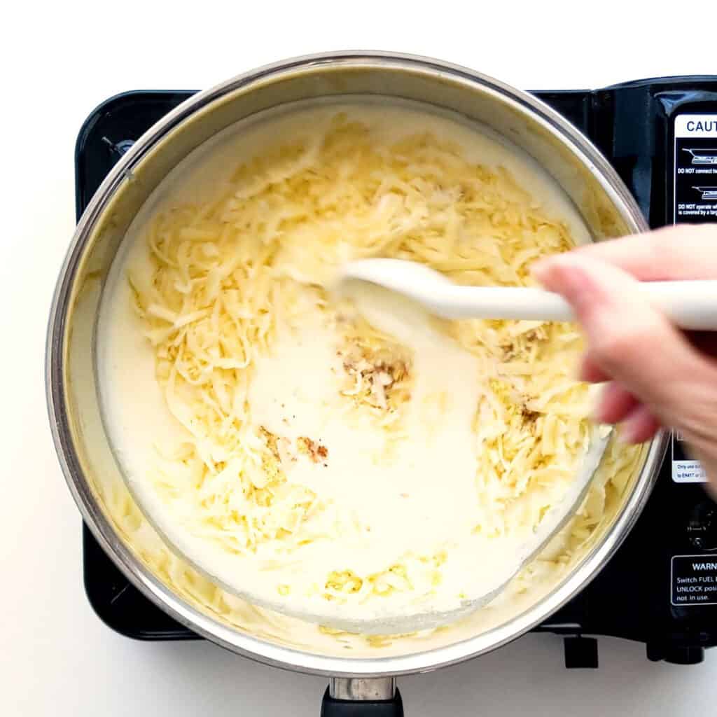 Mixing cheese through white sauce.