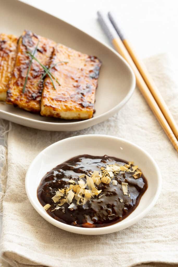 A dark umami sauce, with basted tofu slices in the background.