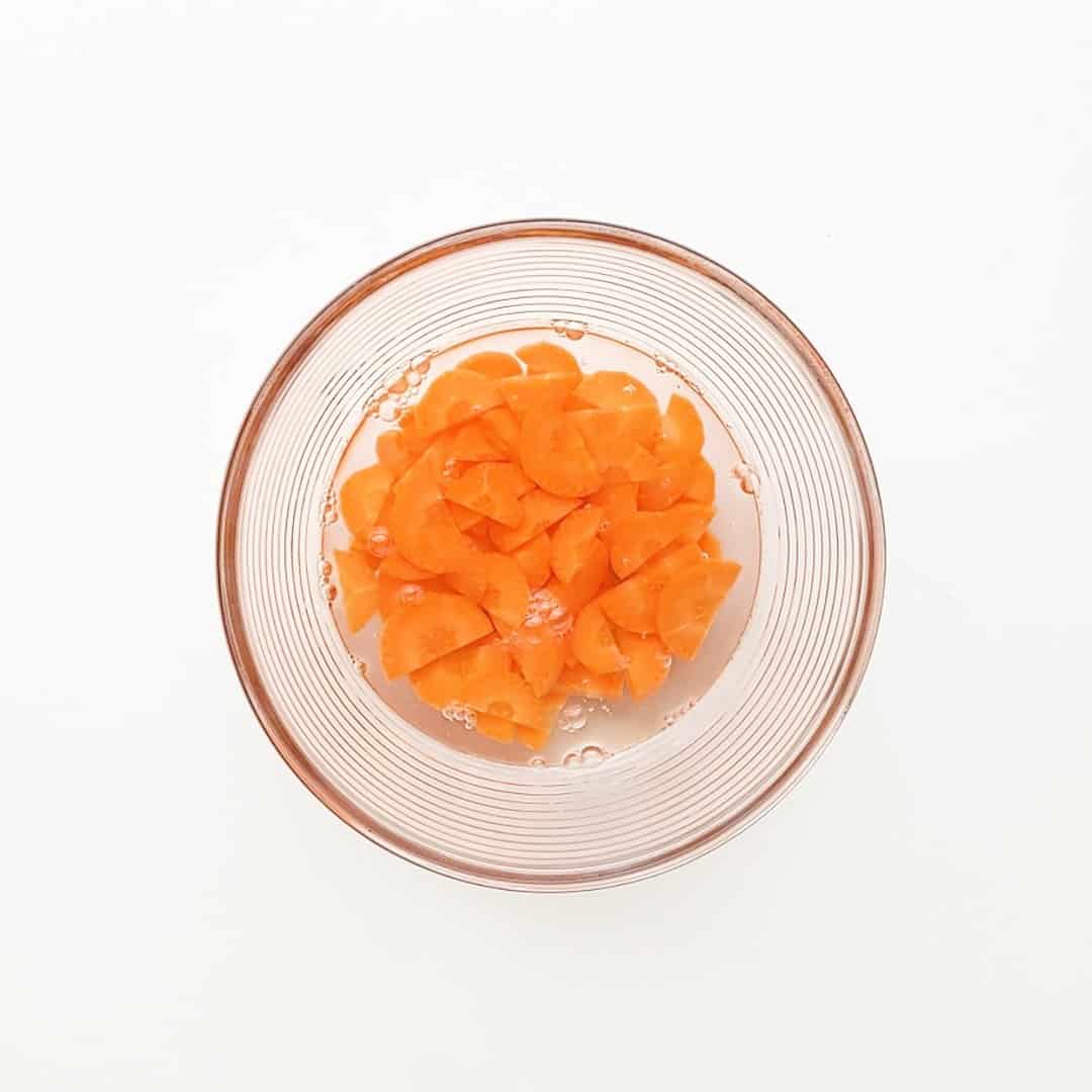 Carrots in a bowl of water, ready to be boiled and softened.