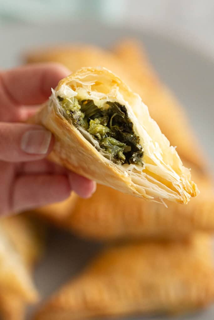 Holding a triangle to show the cheese and spinach filling.