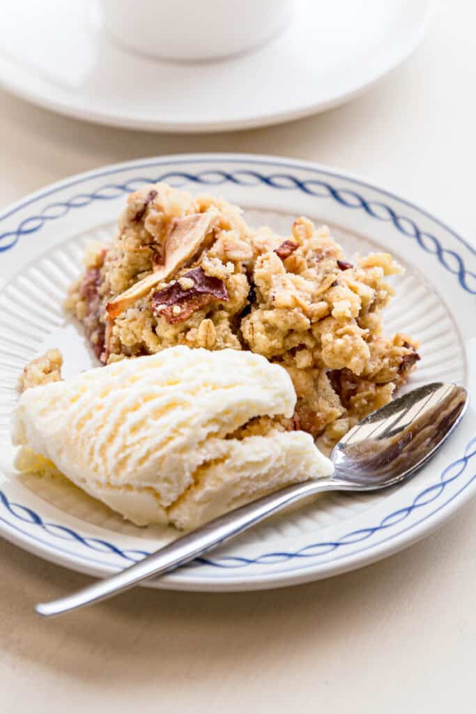 A decorative plate with apple crumble and ice cream, ready to eat.