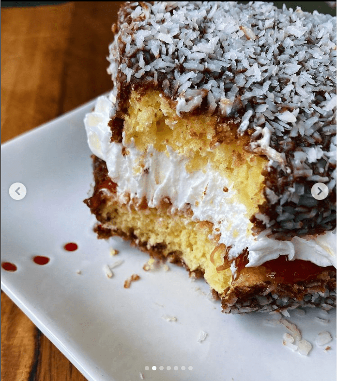 Image of lamington stuffed with jam and cream, with a bite taken out.
