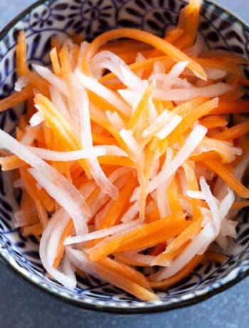 Close up shot of pickled carrots and daikon in a blue bowl.