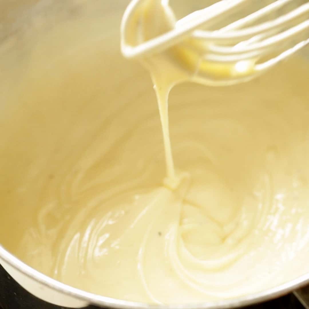 Swirling a whisk in cheese sauce to show the perfect texture.
