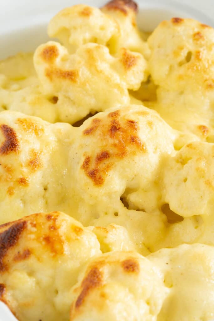 A close up of the golden brown cheese sauce, baked onto the top of cauliflower florets.