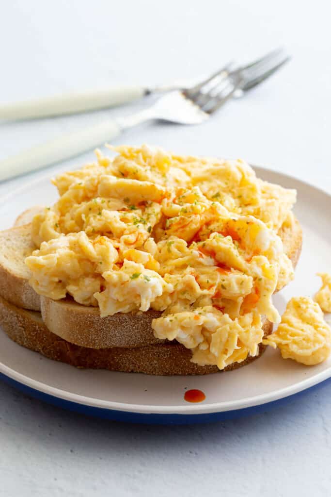 Golden scrambled eggs sit on a plate of fresh toast.