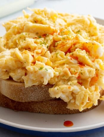 Miso butter scrambled eggs sit on two pieces of toast with a garnish of aonori and rayu chilli oil.