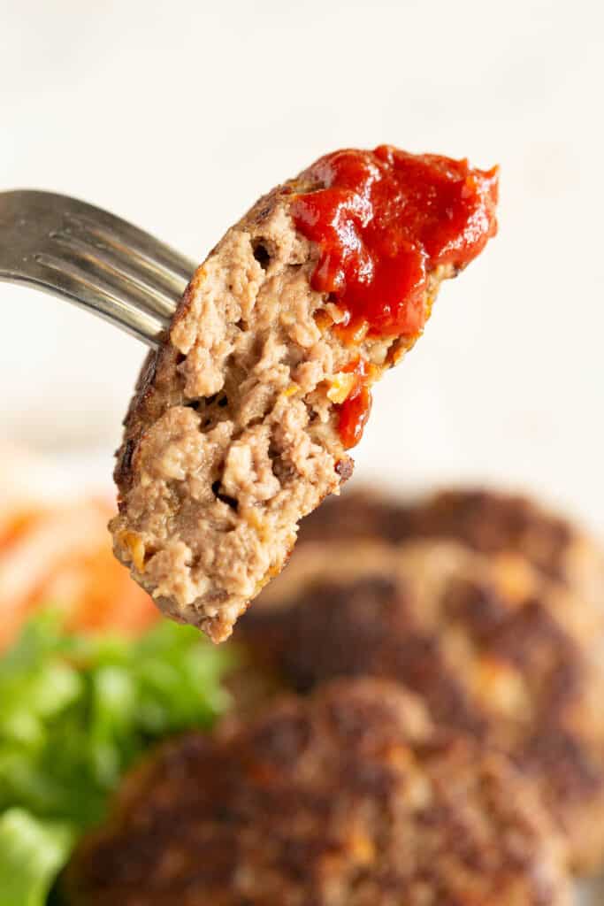 Half a rissole on a fork that's been dipped into tomato sauce.