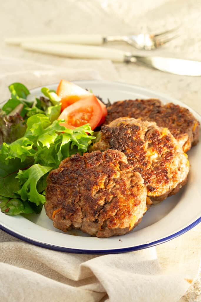 Rissoles on a plate with a salad, sitting in the sunlight.