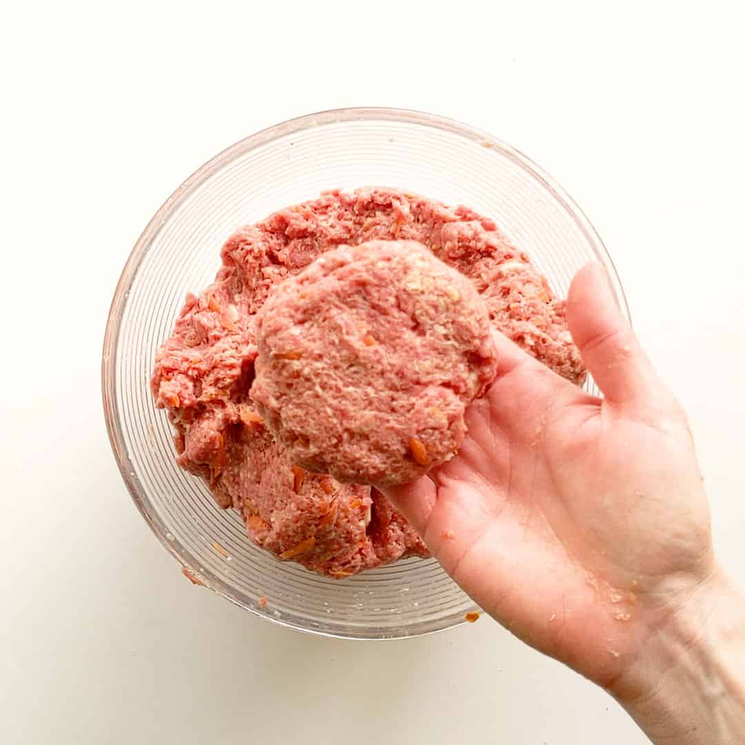 A formed rissole patty sitting on a hand.