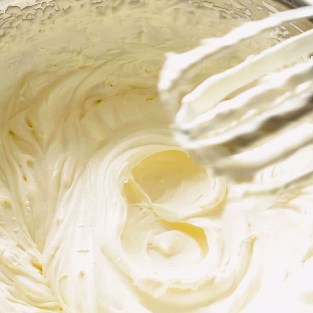 Hand beaters being removed from a bowl of whipped cream.