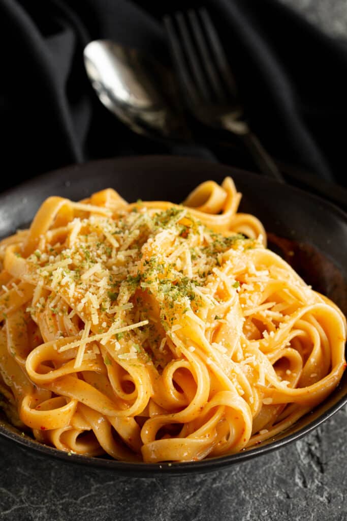 Bowl of creamy gochujang pasta on a dark background.