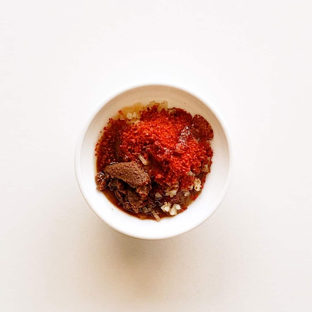 The ingredients for homemade gochujang are piled up on each other in a small white dish, ready to be mixed.