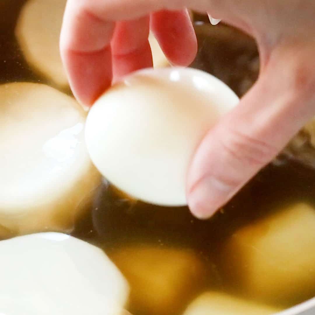 Placing a boiled egg into the oden broth.