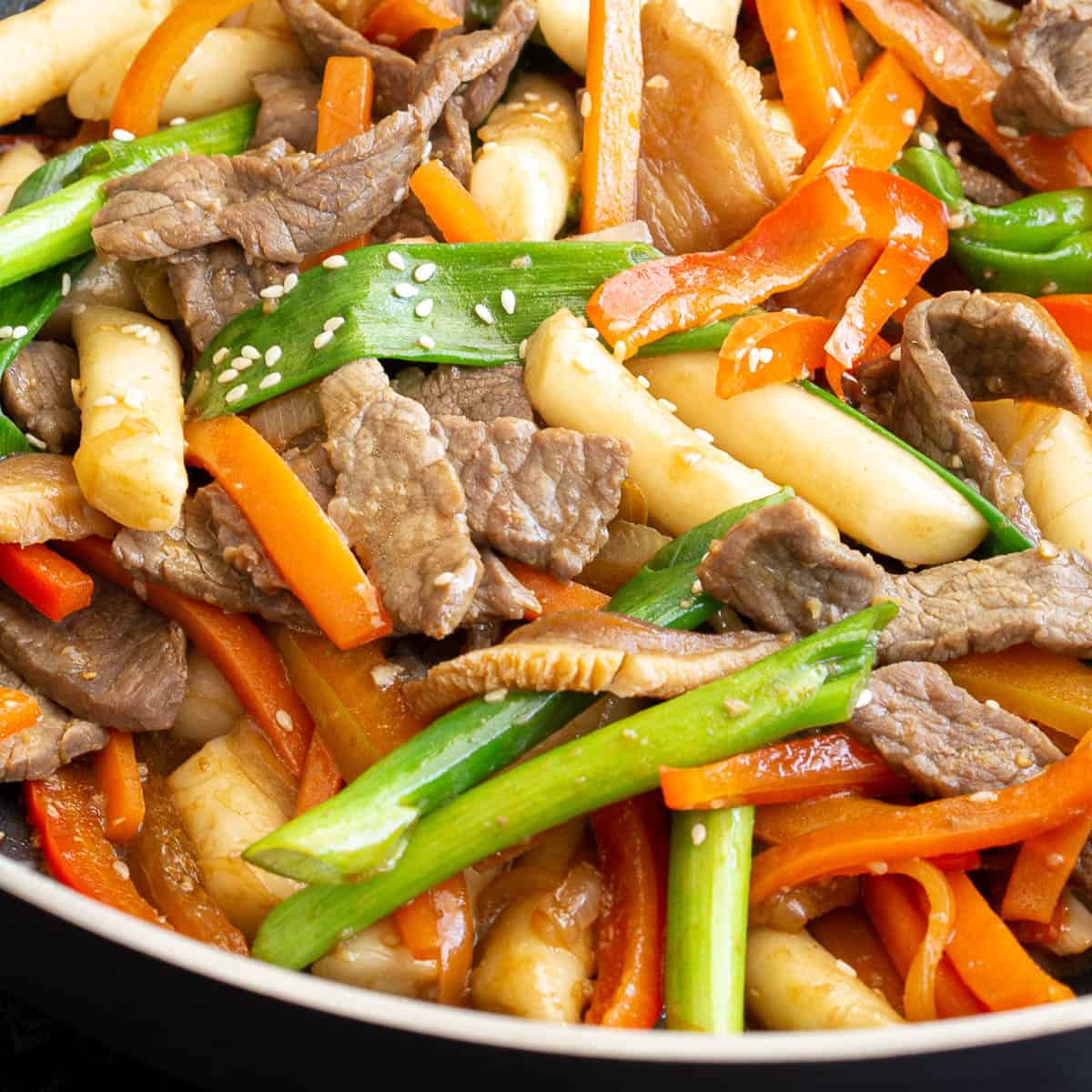 Close up shot of gungjung tteokbokki stir fry showing the cooked beef, rice cakes and vegetables.
