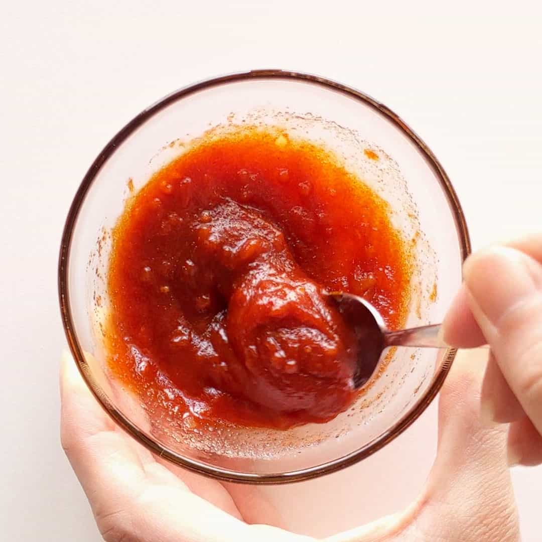 Mixing bright red sauce ingredients in a small bowl.