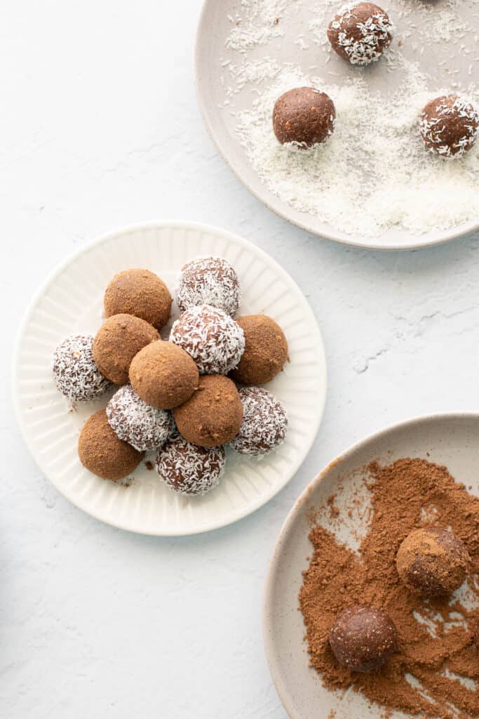 Plates with rum balls being rolled in both milo and coconut.
