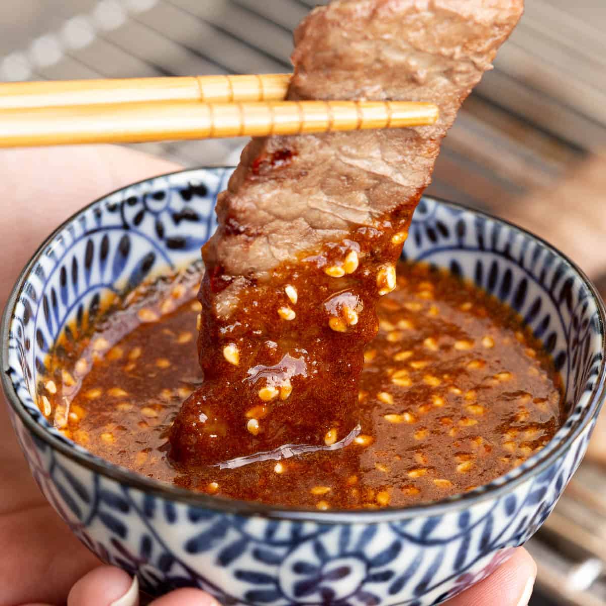 A piece of meat is dipped into homemade yakiniku sauce.