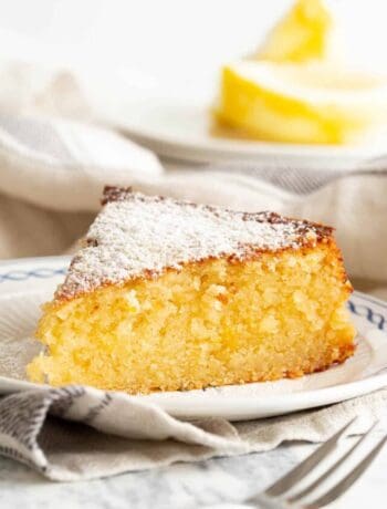 Slice of ricotta cake on a plate with a cake fork in the foreground.