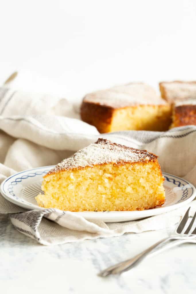Slice of ricotta cake with the remaining cake slices in the background.