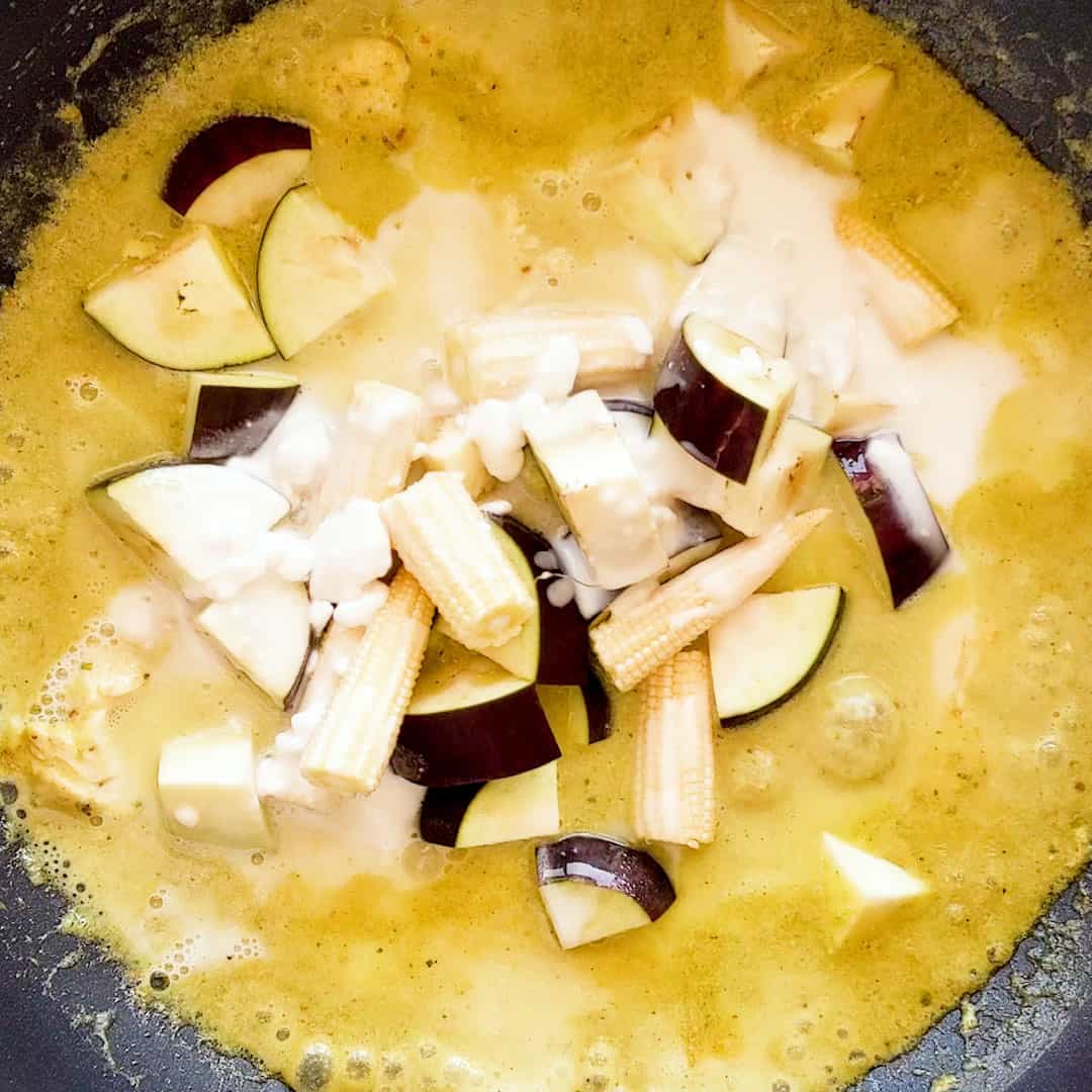 Adding the eggplant, baby corn and remaining coconut milk to the curry.