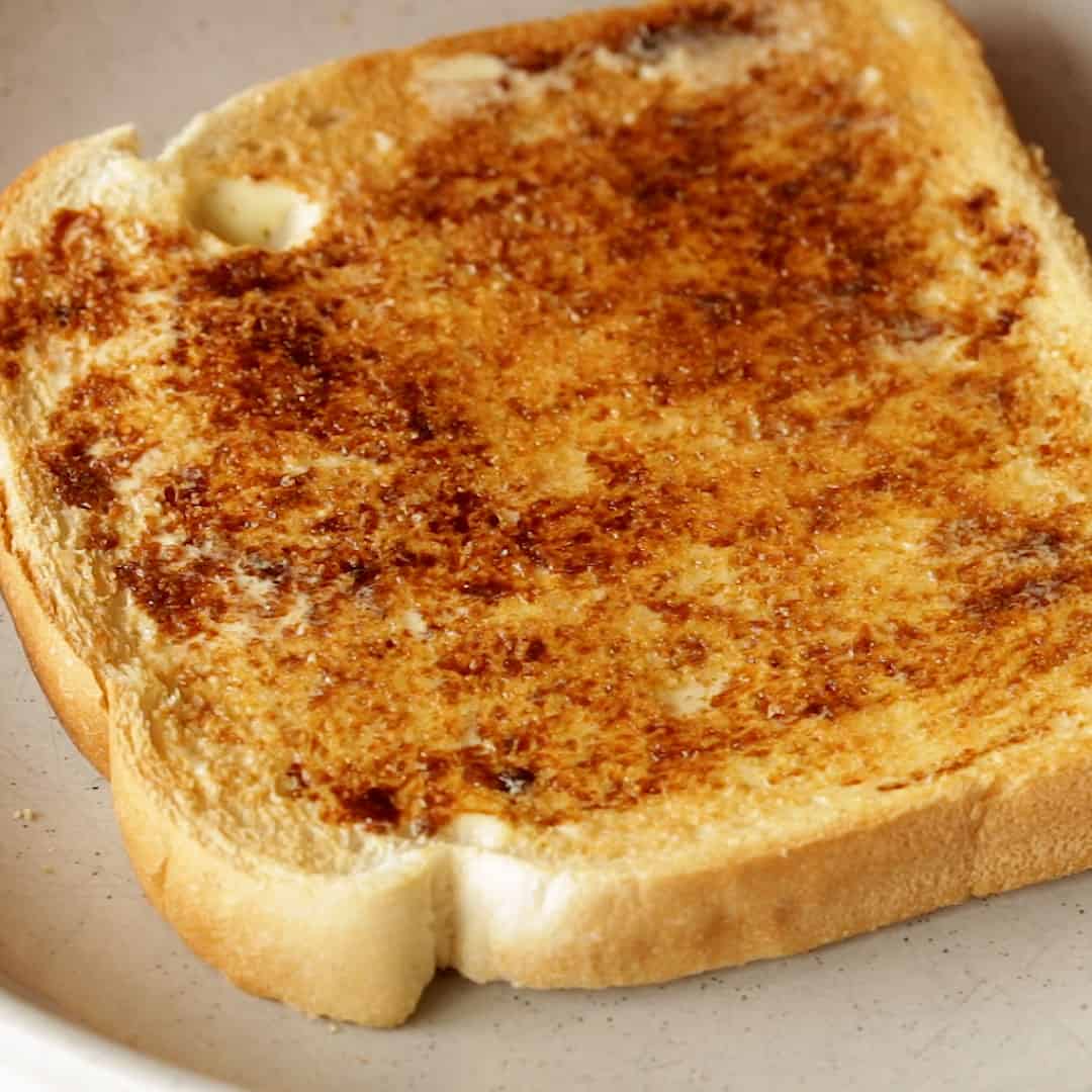 Spreading a light coat of Vegemite on buttered toast.