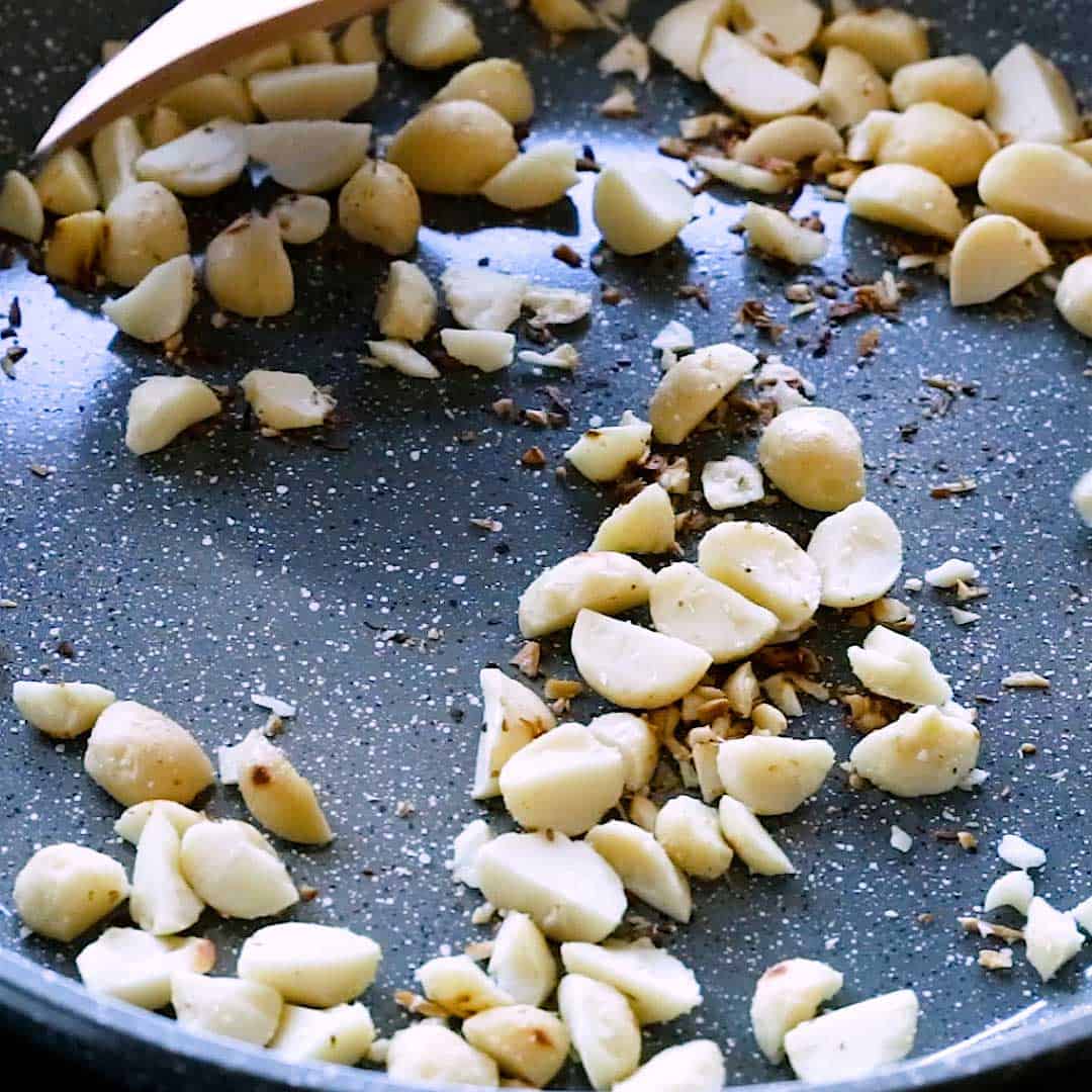 Dry toasting macadamia nuts in a pan.