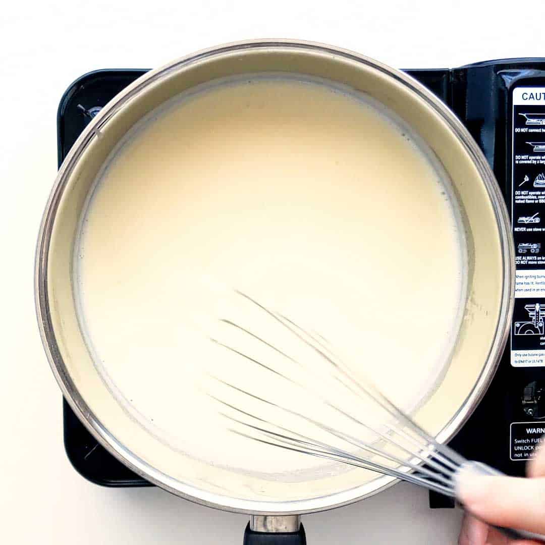 Whisking white sauce as it thickens.