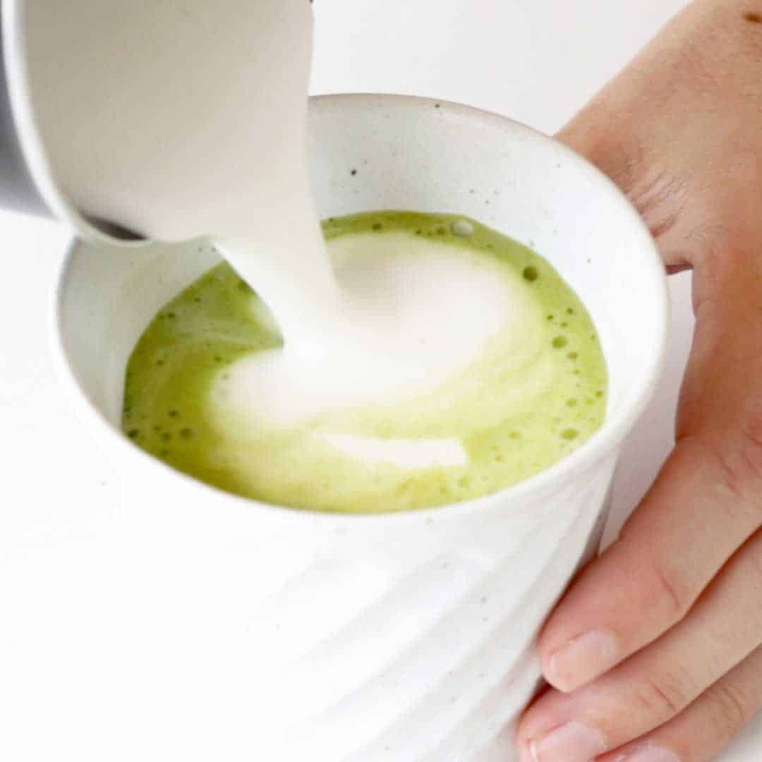 Pouring the frothed milk into the matcha tea.