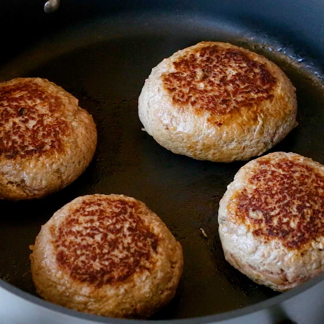 Frying the hamburgs in a large frying pan.