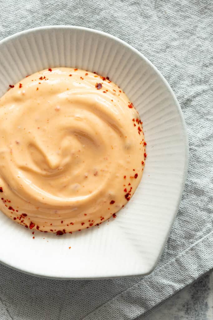 Sriracha mayo with swirls running through it on a white dish.