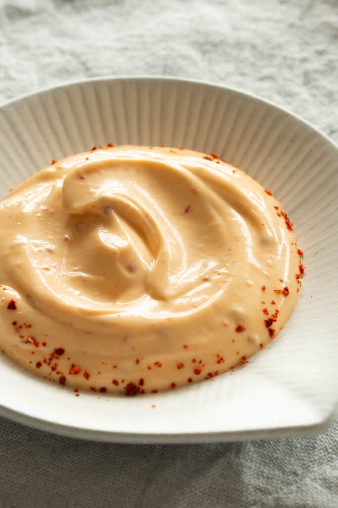 A creamy, light orange spicy dip in a white dish.