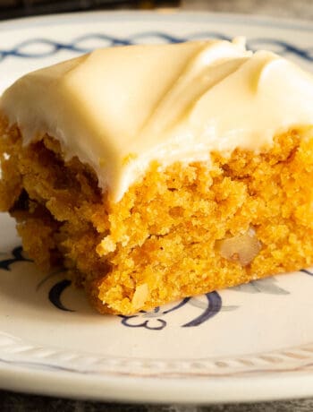 A small square piece of carrot cake on a white plate.