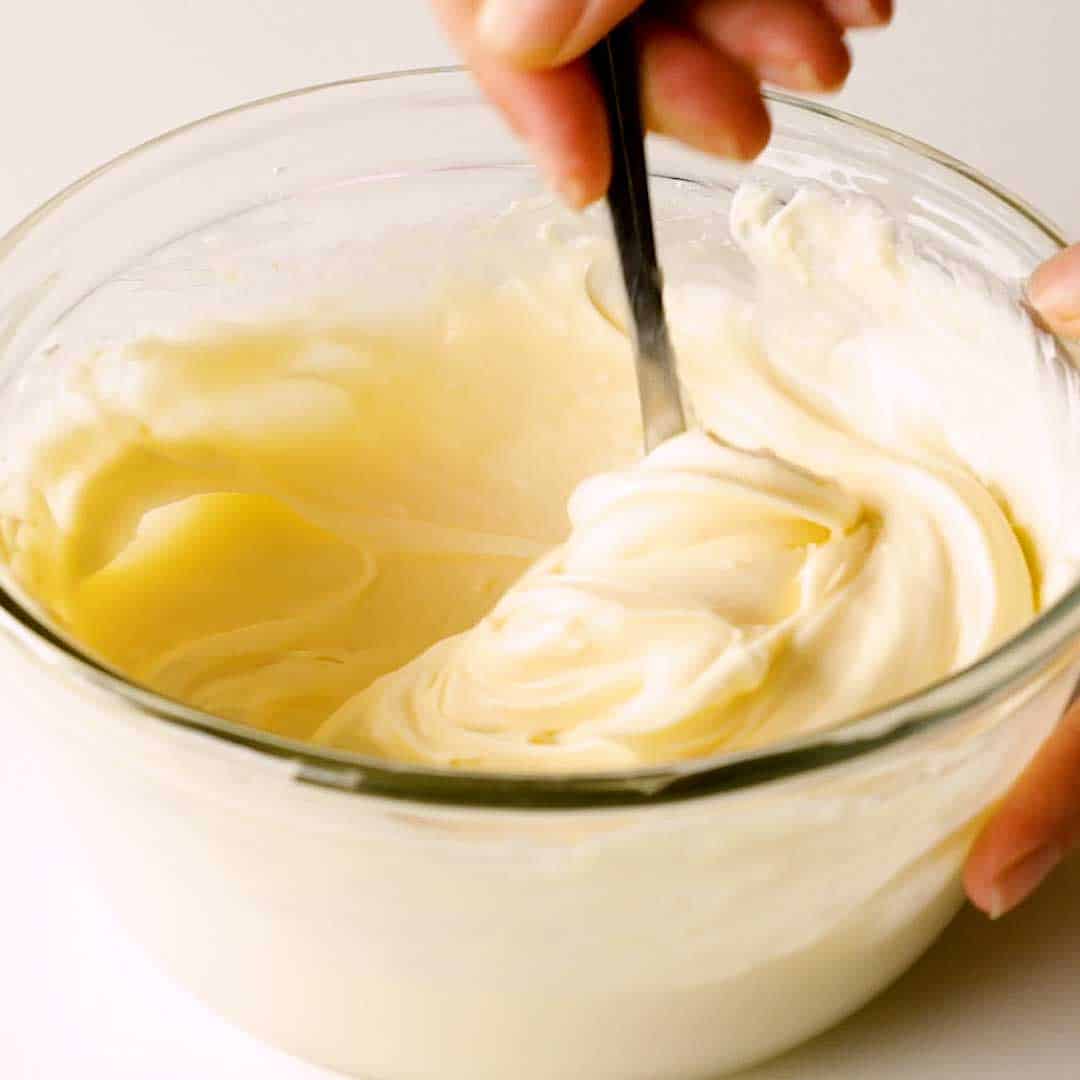 Cream cheese frosting being mixed in a bowl.