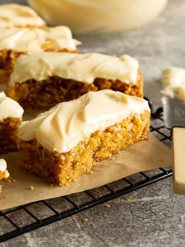 Slices of carrot cake slice topped with cream cheese icing.