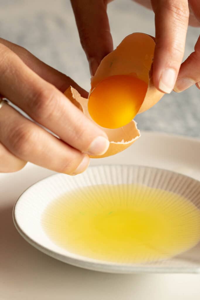 An egg yolk is poured from one half of an egg shell to another.
