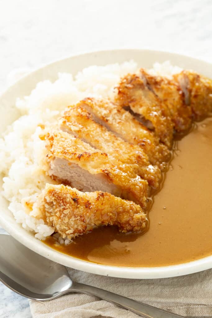 Golden katsu lays on top of sushi rice and curry sauce.
